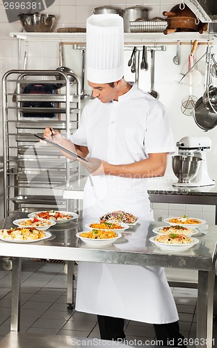Image of Chef With Clipboard Checking Pasta Dishes