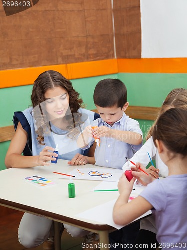 Image of Teacher With Students Painting At Desk