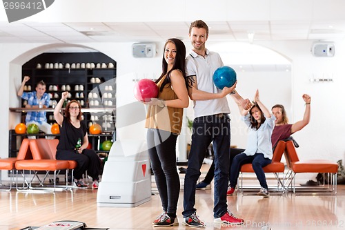 Image of Young Man And Woman With Bowling Balls in Club