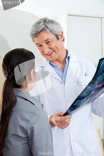 Image of Radiologist Looking At Patient While Holding X-ray