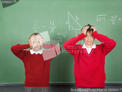 Image of Confused Teenage Students Standing Against Board