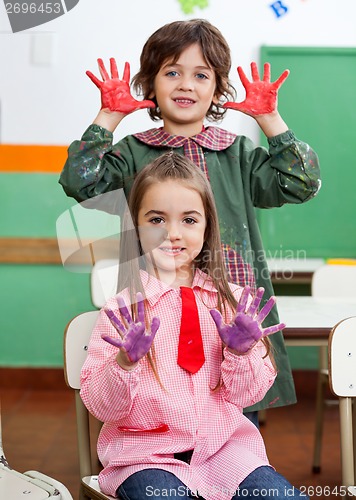 Image of Boy And Girl Showing Colored Hands In Classroom