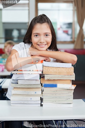 Image of Schoolgirl Leaning On Stacked Books At Desk