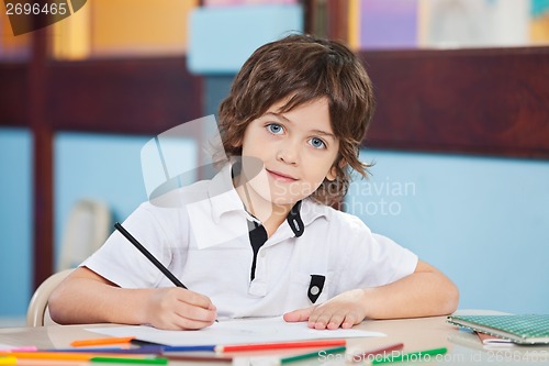 Image of Boy With Sketch Pen And Paper At Desk