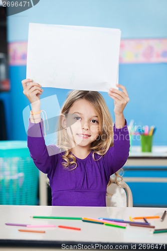 Image of Girl Holding Blank Paper At Desk In Classroom