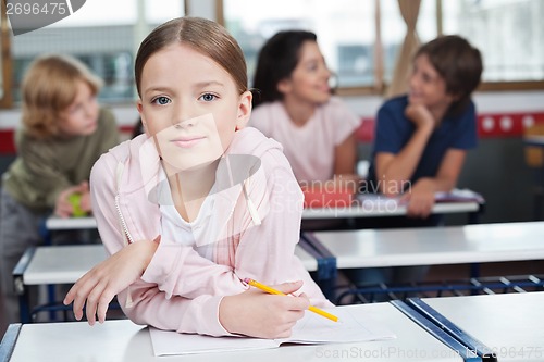 Image of Schoolgirl Leaning On Desk With Students In Background