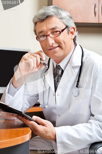 Image of Doctor Sitting At Desk In Clinic