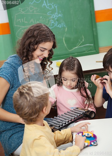 Image of Teacher And Children Playing With Xylophone In Class