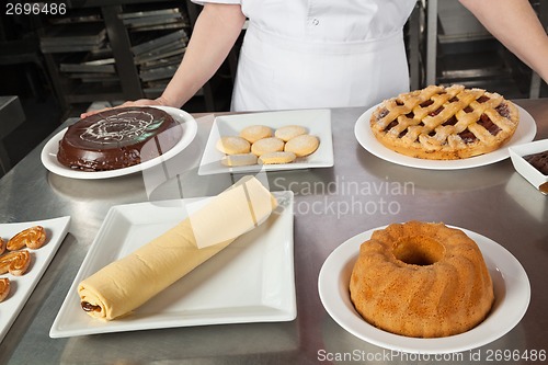 Image of Female Chef With Variety Of Sweet Dishes