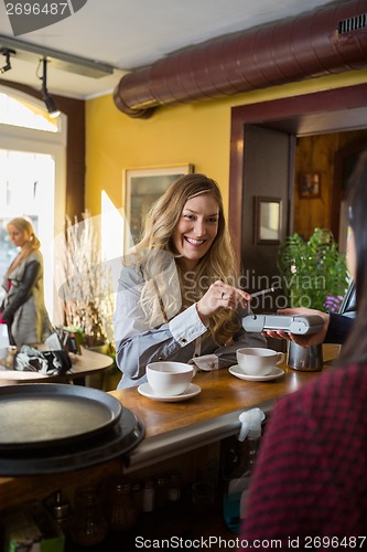 Image of Woman Making Payment Through Mobilephone At Counter