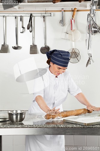 Image of Happy Female Chef Rolling Dough