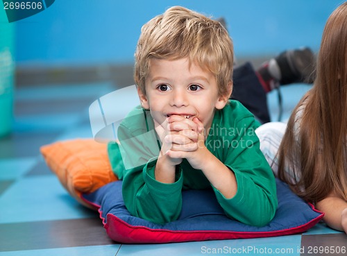 Image of Boy With Hands Clasped Lying On Floor In Kindergarten