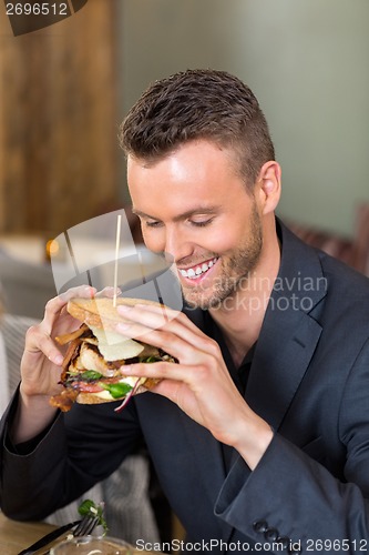 Image of Businessman Holding Sandwich In Coffeeshop