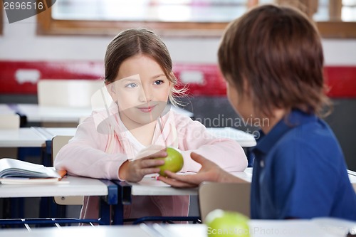 Image of Little Girl Giving Apple To Boy In Classroom