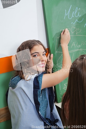 Image of Teacher Writing On Chalkboard In Classroom