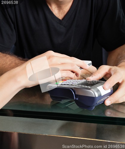 Image of Customer Paying With Mobilephone Over Electronic Reader At Salon