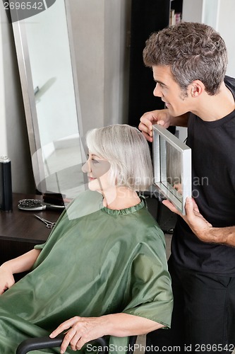 Image of Hairdresser Holding Mirror Behind Senior Woman