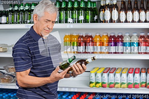 Image of Senior Man Comparing Beer Bottles