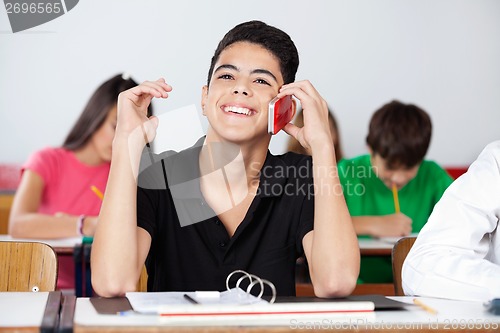 Image of Teenage Male Student Using Phone In Classroom