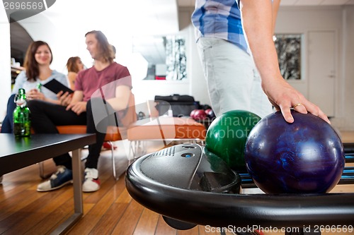 Image of Man Picking Bowling Ball From Rack