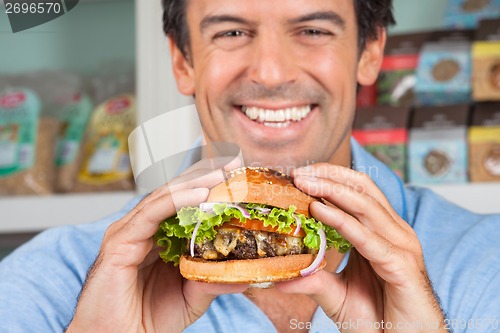 Image of Happy Man Holding Bugger In Grocery Store