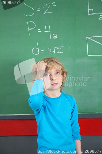 Image of Sad Schoolboy Standing Against Board In Classroom