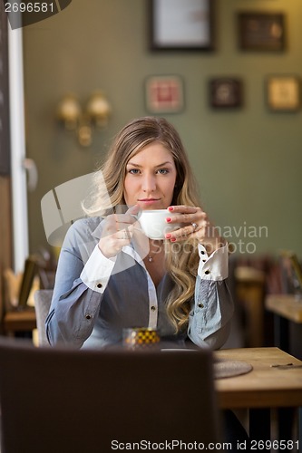 Image of Young Woman Drinking Coffee At Cafe