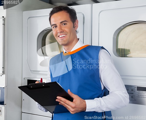 Image of Male Helper Writing On Clipboard In Laundry