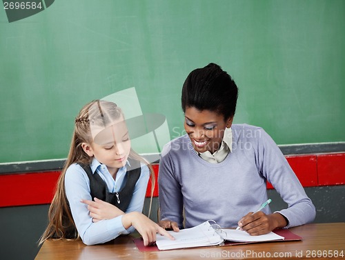 Image of Schoolgirl Asking Question To Teacher At Desk