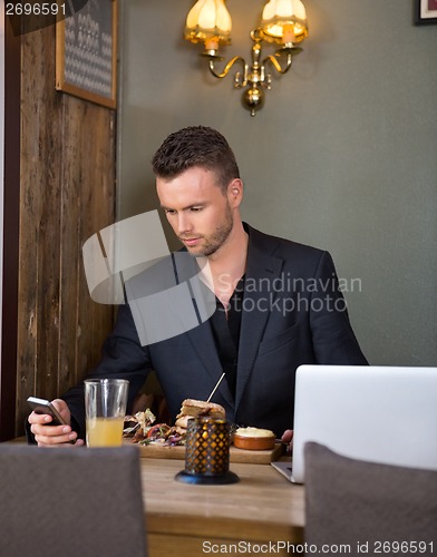 Image of Businessman Messaging On Mobilephone While Having Meal