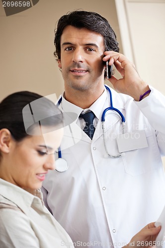 Image of Doctor Answering Call While Standing With Colleague