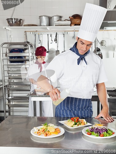 Image of Chef Adding Oil To Dish In Kitchen