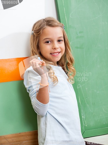 Image of Girl With Chalk Standing By Chalkboard In Class