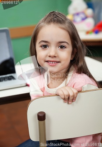 Image of Girl Sitting On Chair With Laptop On Desk In Classroom