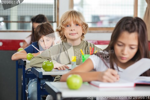 Image of Schoolboy Sitting At Desk With Classmates In A Row