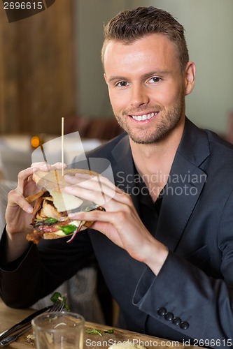 Image of Businessman Holding Sandwich In Restaurant