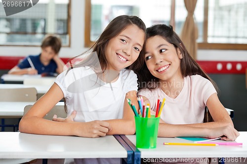 Image of Schoolgirl Sitting With Female Friend At Desk In Classroom