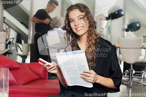 Image of Woman With Mobile Phone And Magazine At Hair Salon