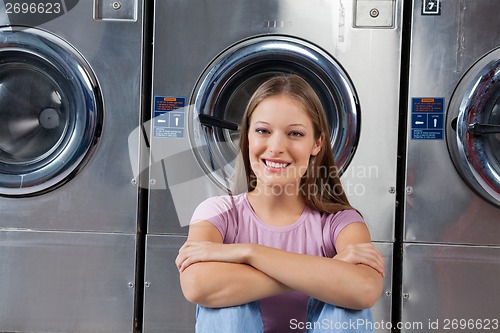 Image of Woman Sitting Against Washing Machines In Laundry