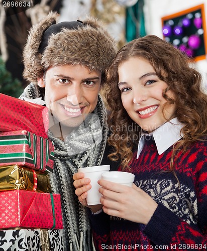 Image of Couple With Presents And Coffee At Christmas Store