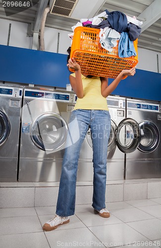 Image of Woman Carrying Basket Of Dirty Clothes In Laundry