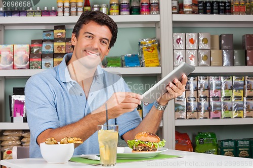 Image of Male Customer With Digital Tablet And Snacks At Table