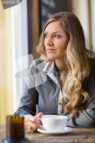 Image of Woman With Coffee Cup Looking Out Window