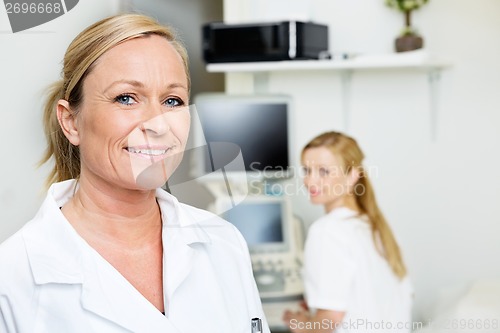 Image of Female Doctor Smiling With Colleague In Background