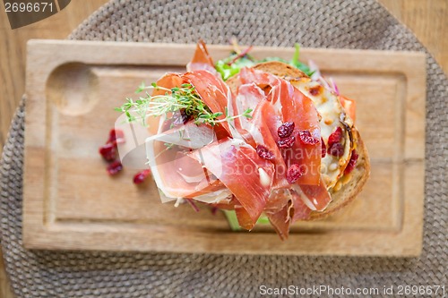 Image of Delicious Parma Ham Sandwich On Wooden Plate