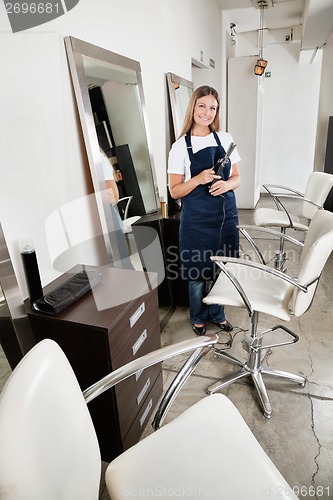 Image of Hairdresser Holding Hair Straightener In salon