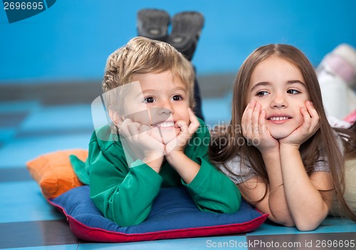 Image of Children With Head In Hands Lying On Floor In Classroom