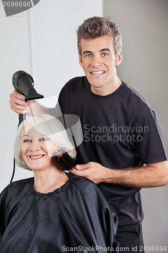 Image of Hairstylist With Dryer Setting Up Woman's Hair