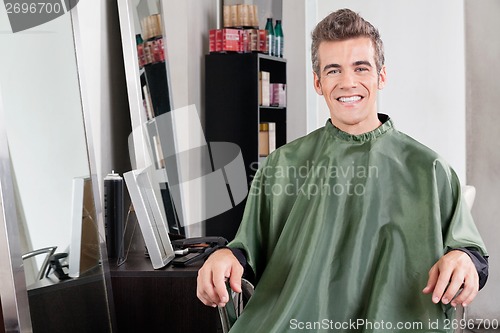Image of Male Customer In Apron Sitting At Hair Salon