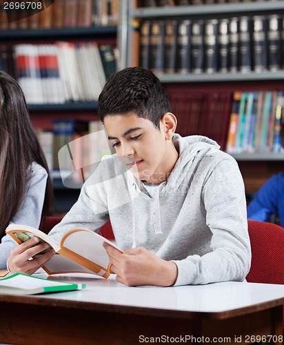 Image of Teenage Schoolboy Reading Book In Library